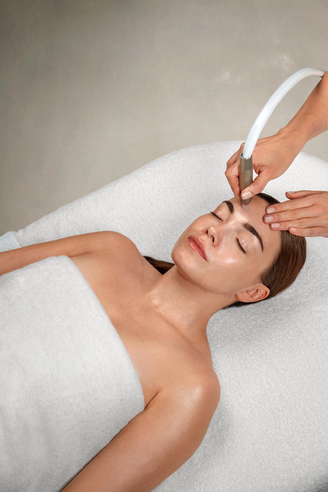Soin de microdermabrasion sur le visage d'une cliente détendue, allongée sur une table de soin